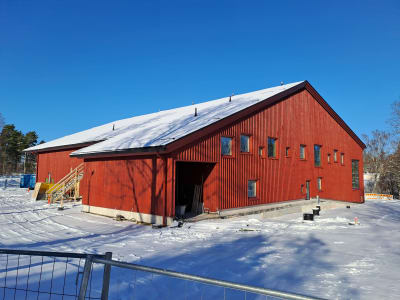 En röd skola, man ser fönster längs ena väggen. Det är Kyrkfjärdens skola i Ingå.