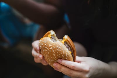 En person håller en hamburgare i händerna.