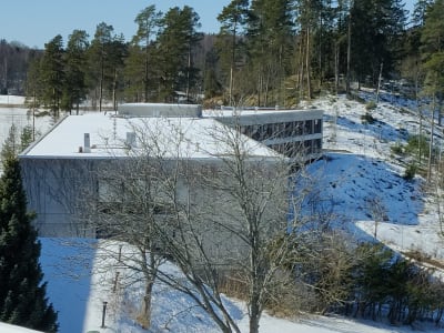 En grå byggnad som är omgiven av skog.