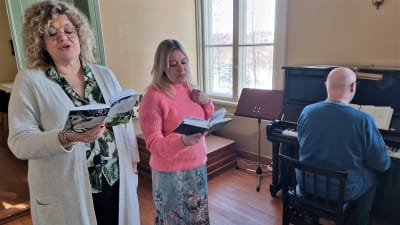 två personer sjunger och en spelar piano