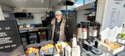 Kvinna med dunväst bakom cafédisk på Åbo salutorg.