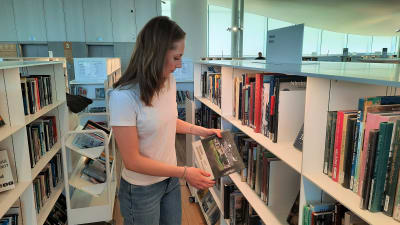 Tiffany Romar tittar på en bok på biblioteket.