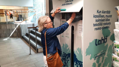 Arja Jokiniemi sätter en påse med textilavfall i insamlingen.