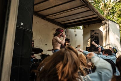 En rocksångare med bar överkropp sjunger på en scen bakom en entusiastisk publik.