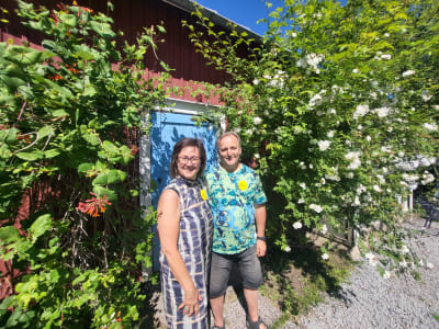 En kvinna och en man framför ett rött uthus. 