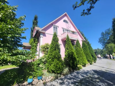 Ett rosa hus med en lummig trädgård.