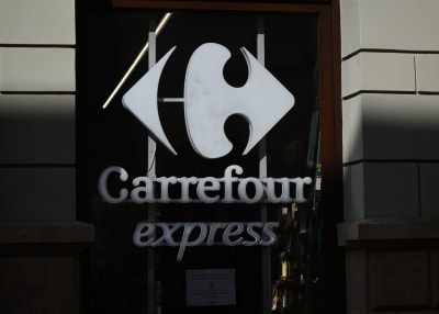 En vit skylt med en logo och texten "Carrefour express". Bakgrunden är mörk.