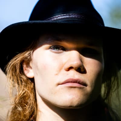 Leo Korte katsoo kameraan ulkona aurinkoisessa säässä stetson hattu päässään.