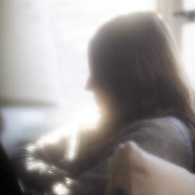 Suddig bild i profil av en ung kvinna som sitter i en soffa.