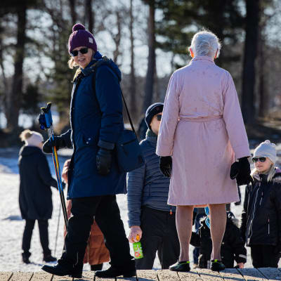 Ihmisiä ulkoilemassa meren rannalla.