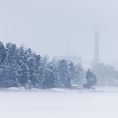 Värmekraftverk syns i dimma i ett mycket snöigt landskap.