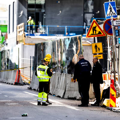 Polisens tekniska utredare utreder platsen där bron rasade. De står i grupp på gatan.