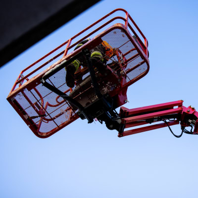 En byggarbetare i korgen på en skylift.