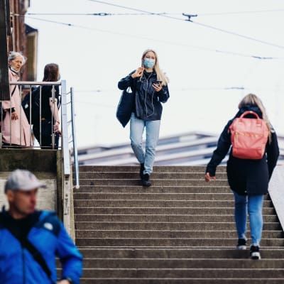 En kvinna med munskydd går ner för en trappa i Helsingfors centrum.