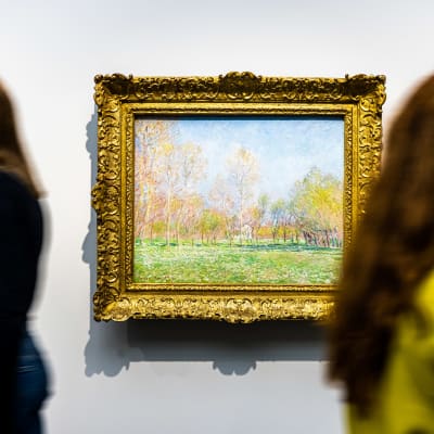 Henkilöitä kävelee Claude Monetinteoksen edestä taidemuseossa.