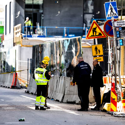 Polisens tekniska utredare utreder platsen där bron rasade. De står i grupp på gatan.
