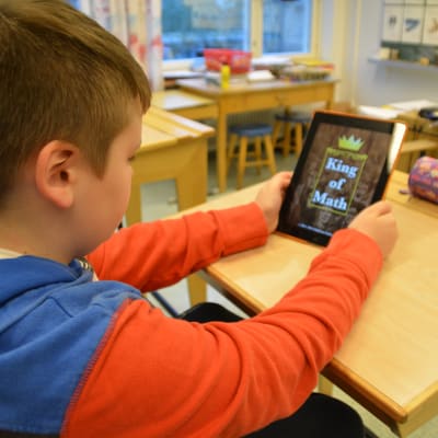 Pojke använder en pekplatta för att räkna matematik.