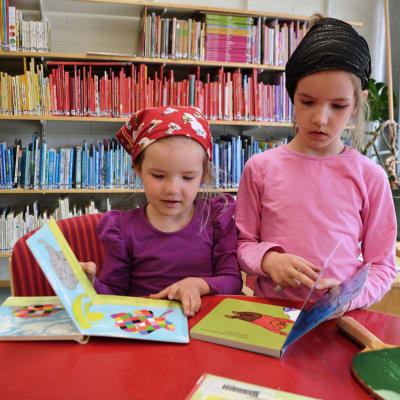 Jemina och Alina Riihimäki bläddrar i böcker i Strömfors gamla bibliotek.