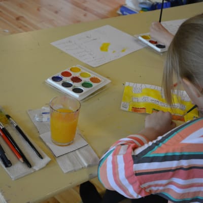 Flicka målar med vattenfärger.