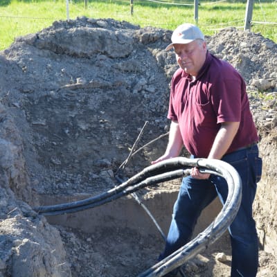 Stefan Juslenius håller i elkablen som grävts ner på hans gård i Mjölbolsta.