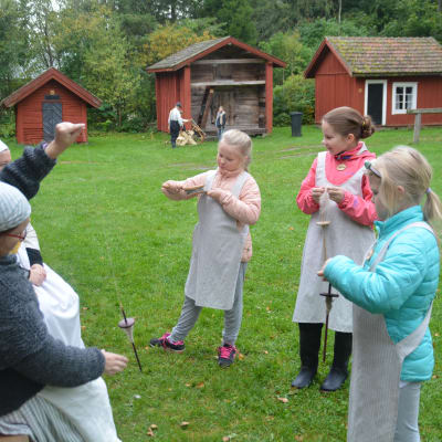 Elever från Merituulen koulu spinner garn på tidsresa vid Gammelgården i Ingå