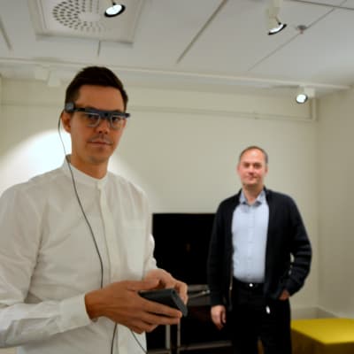Utvecklaren Joachim Majors visar glasögonen som mäter ögonrörelser. Verksamhetschefen Kimmo Rautanen står i bakgrunden.