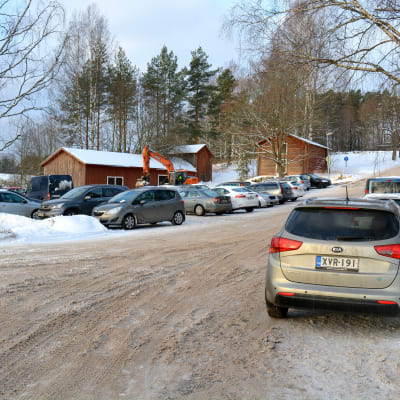 Bilar står parkerade längs snöig sandväg