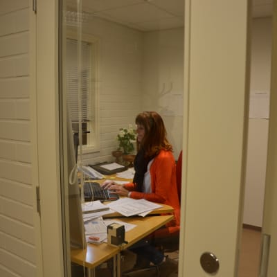 Kvinna sitter i ett arbetsrum och jobbar på dator.