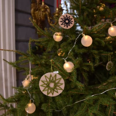 Juldekorationer av paff och garn hänger i julgran.