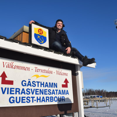 Benjamin Lundin har klättrat upp på en välkomstskylt i Ingå.