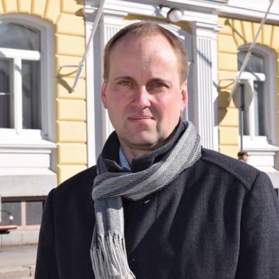 En man i halsduk och jacka står utanför stadshuset i Ekenäs. Raseborgs stadsdirektör Tom Simola.