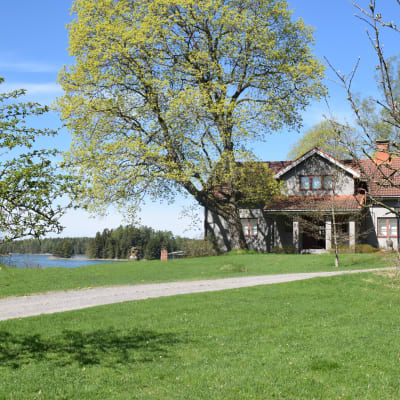 Större gårdsbyggnad med hav i bakgrunden.