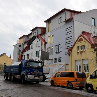 En liten lastbil står vid en byggarbetsplats i ett flervåningshus.