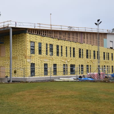 Ett två våningar stort hus byggs, ställningar på taket, gul isolering på väggarna.