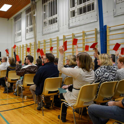 Alla närvarande på invånarmöte om skolornas framtid i östra Borgå viftar med röda lappar.