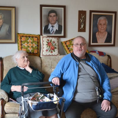 Eila och sonen Ove sitter tillsammans i hennes soffa, Eila har en rollator