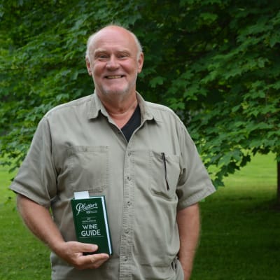 Bror West står med en vinguide i handen i en lummig, grön miljö.