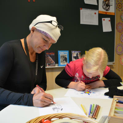 Satu Partanen tecknar med barn i gammelbacka skola.