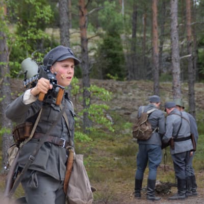 Määttä (David Sandqvist) med ett vapen på axeln i pjäsen Okänd soldat i Harparskog.
