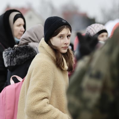 Flyktingar står utomhus vid Ukraina-Polen gränsen.