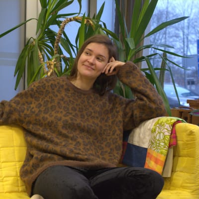 Maria Sann sitter på en gul soffa.