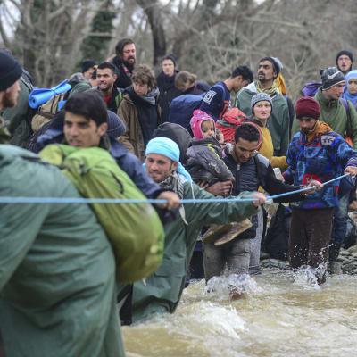 Flyktingar tar sig över en flod för att hitta alternativa rutter för att ta sig till den grekisk-makedoniska gränsen nära Idomeni.