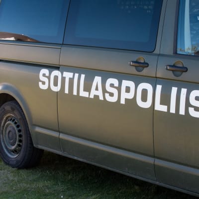 En militärgrön minibuss med texten Sotilaspoliisi på sidan.