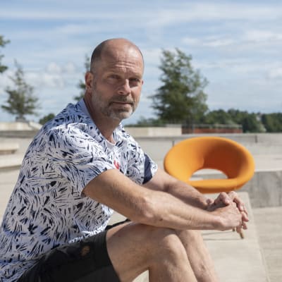 Toimittaja Pasi Toivonen istuu Kalasataman rannassa ja kasoo suoraan kameraan.