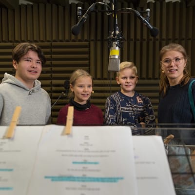 Fyra ungdomar står i en studio och skådespelar i ett audiodrama. De ser mot regissören som står bakom kameran.