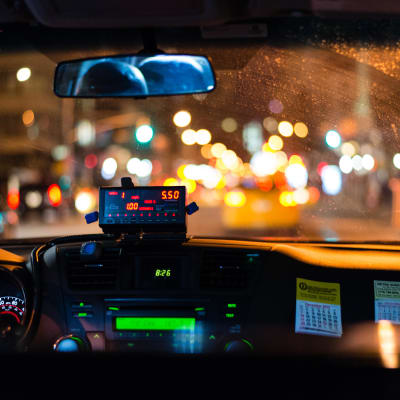 Förar- och passagerarsätet i en taxibil fotograferat från baksätet.
