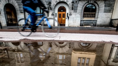 En cyklist cyklar invid en stor vattenpöl i Åbo.