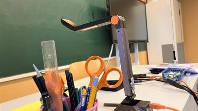 Ett bord i ett klassrum med saxar och pennor.