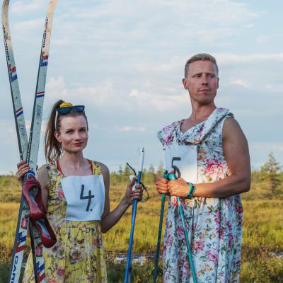 Egenlandin juontajat Hannamari Hoikkala ja Nicke Aldén seisovat suolla kukkumekot yllään ja sukset ja sauvat käsissään.