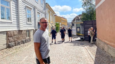 En man står i Gamla stan i Borgå. Han tittar in i kameran och ler.